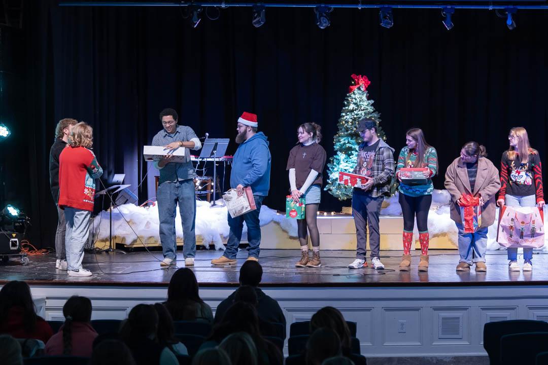 Students open presents on the chapel stage